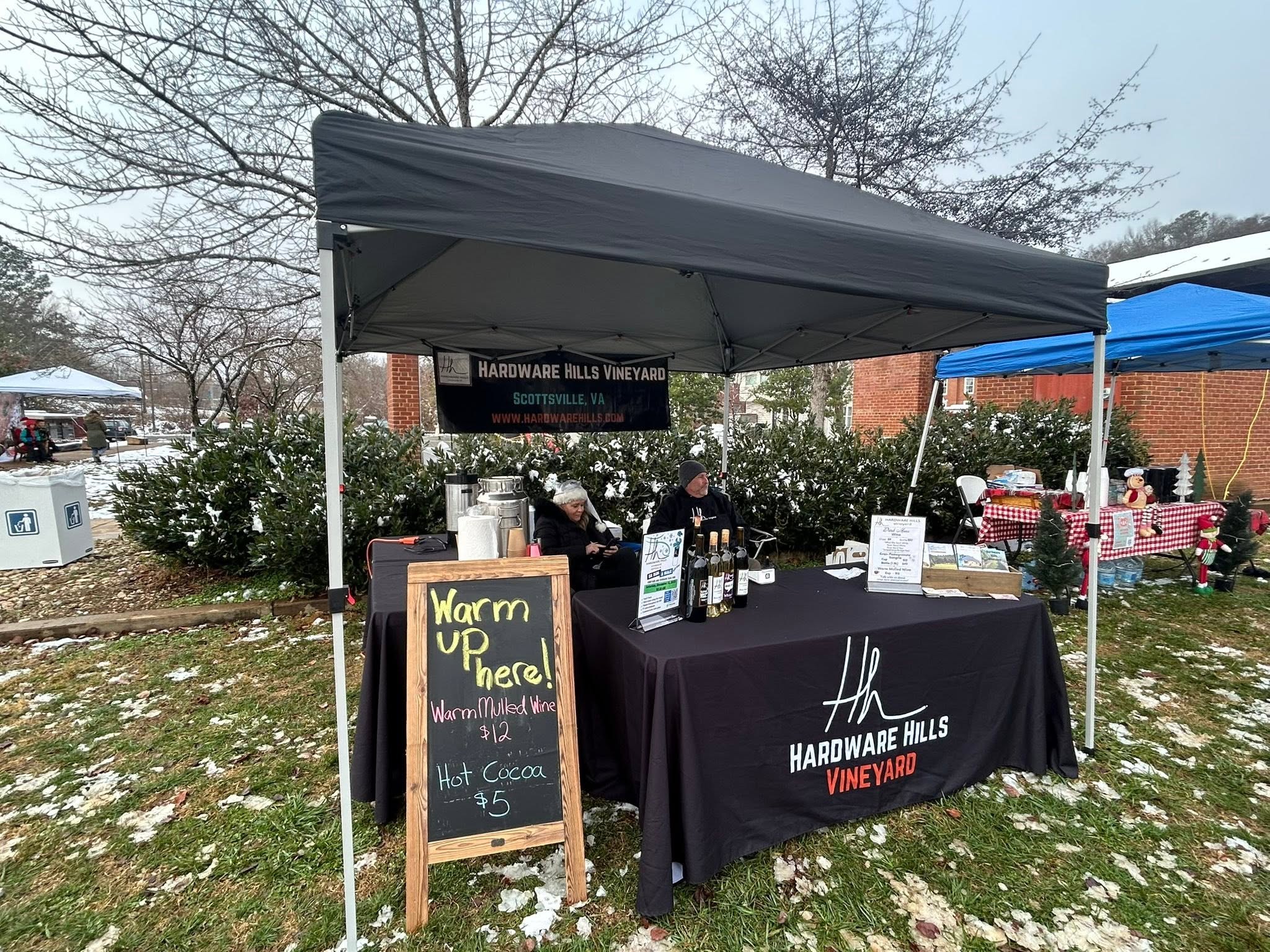The Hardware Hills Vineyard booth with a chalkboard offering warm mulled wine and hot cocoa