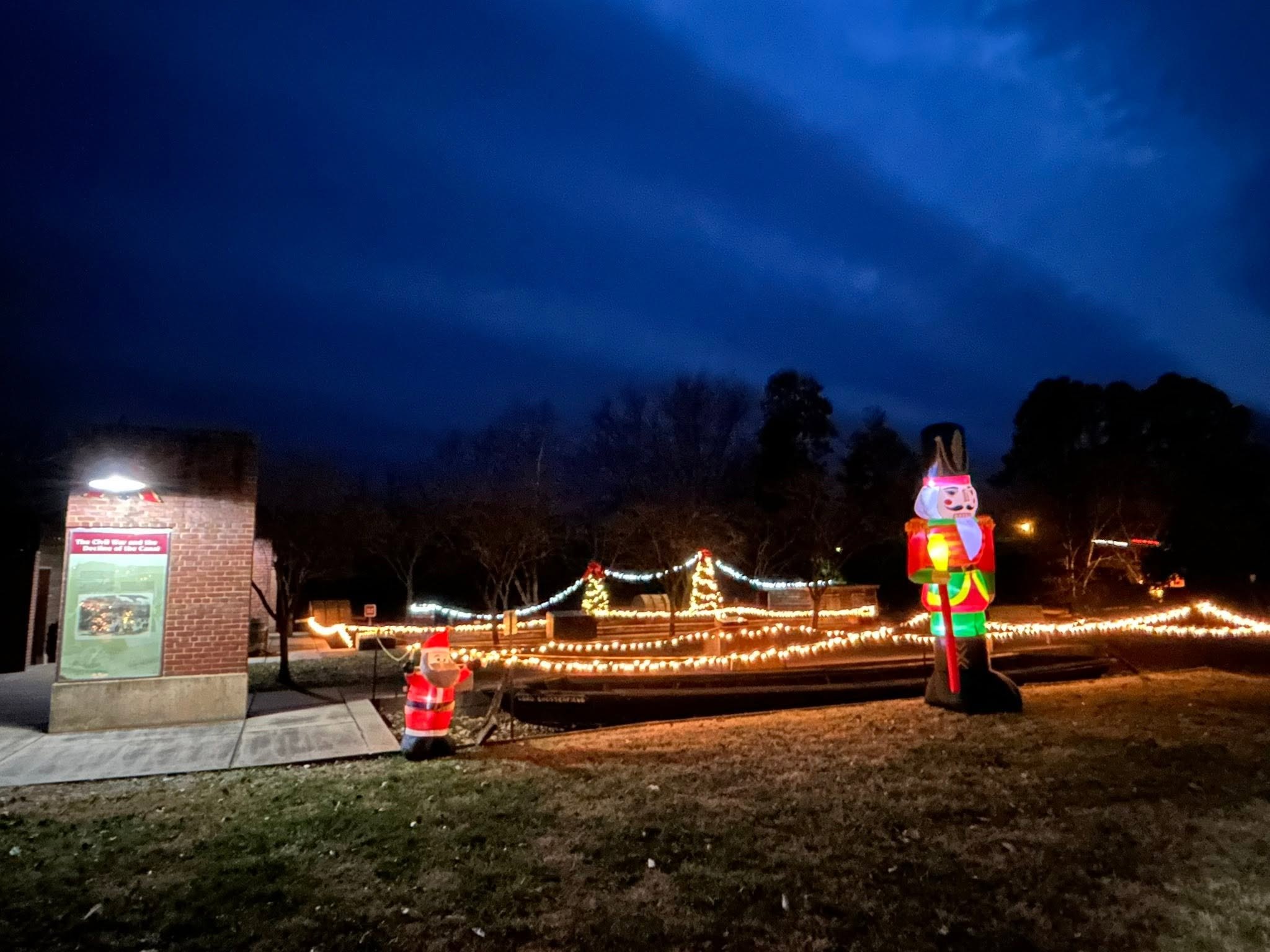 Canal Basin Square at night, with the batteau outlined in lights, a nutcracker and a Santa figure